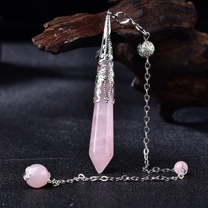 Detail of rose quartz hexagonal pendant with vintage silver cap hanging on dark wood