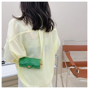 Detail of green quilted cylindrical jelly bag with gold chain and twist lock mechanism