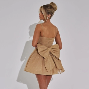 Detail of elegant champagne cocktail dress featuring a large bow and sparkly mesh fabric