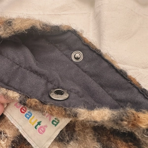 Gros plan détaillé du sac en peluche léopard avec bouton pression argenté et doublure interne
