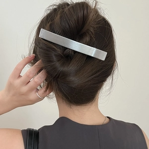 Barrette rectangulaire en métal argenté brossé portée sur un chignon élégant