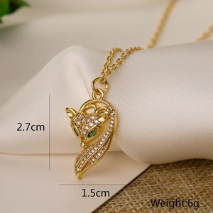 Golden fox pendant necklace with green eyes and clear crystals on white linen fabric