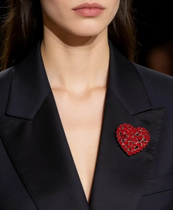 Detail of a red heart-shaped brooch with sparkling rhinestones on a dark suit lapel