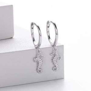 Close-up of S925 sterling silver seahorse drop earrings on a white geometric stand