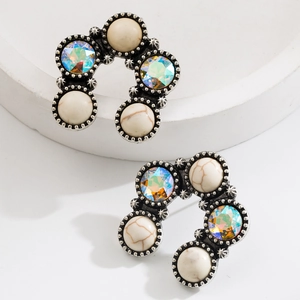 Detail of silver U-shaped earrings with white turquoise and iridescent gemstones