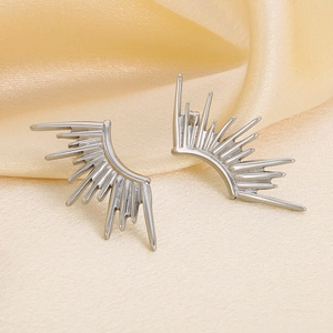 Detailed view of silver sunburst earrings on elegant yellow satin fabric background