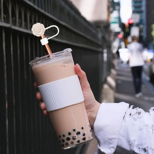 Detail of white flower straw topper on a textured tumbler sleeve in a city setting