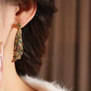 Gros plan détaillé de boucles d'oreilles fleurs vintage avec cristaux verts et rouges