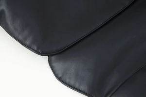 Vue détaillée de la texture du cuir PU noir et des coutures doubles de qualité sur la manche