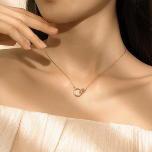 Close-up of interlocking Mobius double ring necklace in rose gold worn on a model neckline