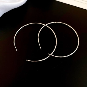 Détail de boucles d'oreilles créoles argentées martelées avec finition métallique