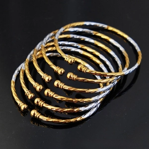 Detailed close-up of stacked gold and silver twisted bangles with round beaded ends