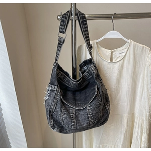 Détail d'un sac bandoulière en jean noir rétro avec bords effilochés et poches
