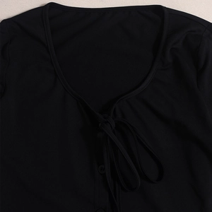 Detail of black V-neck lace-up ribbed top with matching buttons and soft knit texture