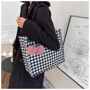Close-up of houndstooth tote bag featuring decorative pink plush cherry charms