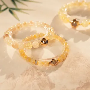 Elegant citrine beaded bracelet with 18K gold heart charms in natural sunlight