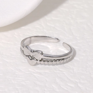 Detailed top view of silver bow and heart open ring with beaded band on white surface