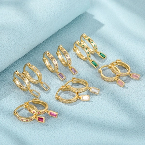 Macro shot of colorful rectangle zircon pendants on gold textured silver hoop earrings
