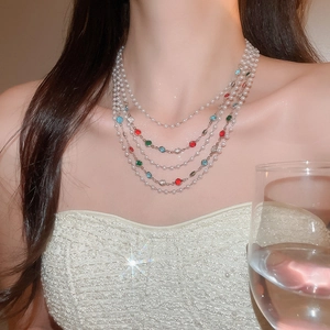 Détail du collier de perles et gemmes colorées superposé porté par un mannequin