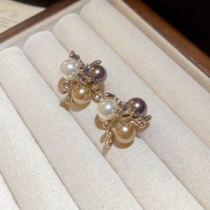 Close-up of pearl flower earrings in coffee and gold tones on beige velvet jewelry box