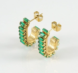 Detail of gold-plated U-shaped earrings featuring emerald-cut green cubic zirconia stones