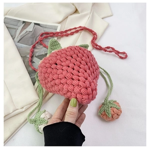 Close-up of handmade crochet strawberry bucket bag showing knit texture and leaf detail