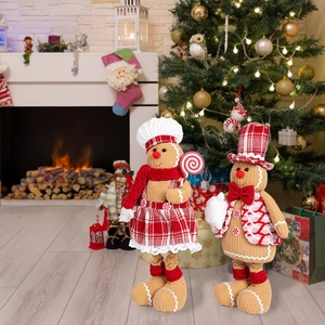 Detail of gingerbread plush dolls with chef hats in a cozy Christmas fireplace setting
