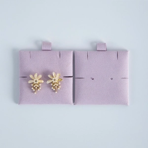 Detail of floral earrings with pearls and rhinestones on purple velvet display cards