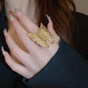 Macro detail of gold plated butterfly ring with pearl on hand showing brushed texture