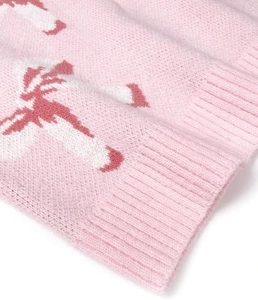 Close-up of pink knit sweater with candy cane patterns and ribbed cuffs detail