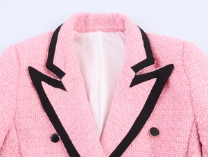 Detail eines rosa Tweed-Blazers mit schwarzer Kontrastpaspel und Knöpfen mit Goldrand