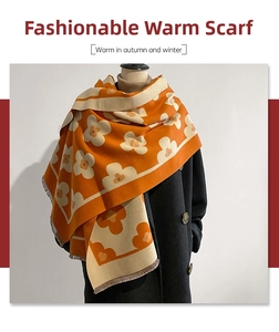 Close-up of bright orange floral knit scarf with fine tassel fringe on black coat