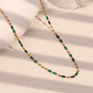 Detailed macro view of 18K gold-plated beads and green cylinder stone on the necklace