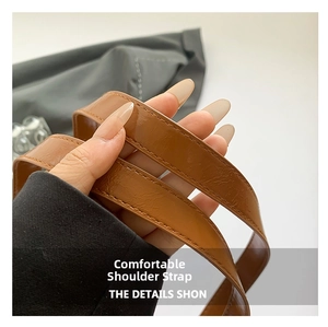 Detailed close-up of brown leather bag strap with fine stitching and glossy texture