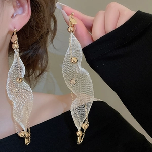 Close-up of long gold mesh tassel earrings with pearls on model showing texture