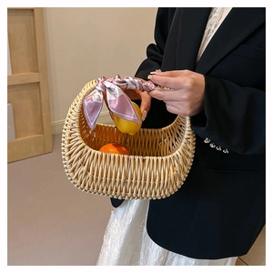 Detail of hand-woven rattan basket bag featuring decorative floral scarf on handle