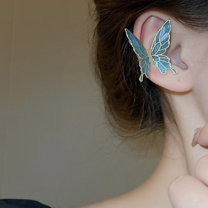 Detailed close-up of blue butterfly ear cuff in gold-plated alloy on a female model