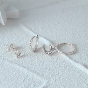Macro detail of S925 silver earring set with star, moon charms and cubic zirconia stones