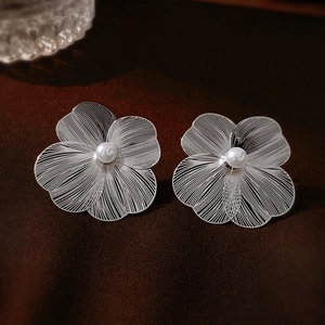 Gros plan de boucles d'oreilles fleurs argentées avec perles sur fond de velours sombre