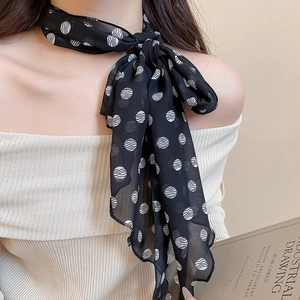 Close-up of black silk scarf necklace with white polka dots tied around the neck