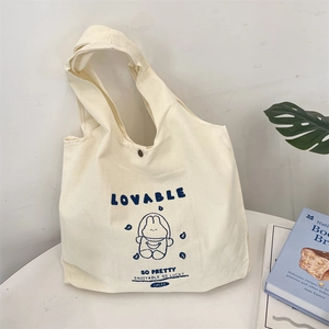 Detail of a canvas tote bag featuring a cute blue cartoon bunny print and snap button