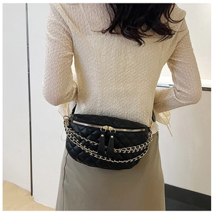 Detail of black quilted leather waist bag with multi-layer gold chain and dual metal zippers
