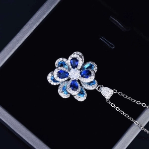 Detailed view of a silver flower pendant necklace with blue and clear zircon crystals