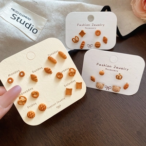 Dettaglio di orecchini a perno a forma di pasticceria carina su una carta da lunedì a domenica