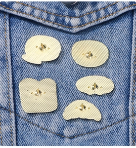 Vue macro du dos de 5 pin's de dessin animé en alliage doré sur du denim bleu
