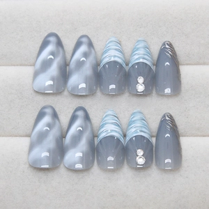 Blue stiletto press-on nails with cat-eye effect, marble texture, and silver accents