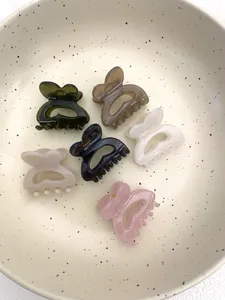 Détail de six pinces à cheveux papillon colorées dans un bol en céramique décoratif