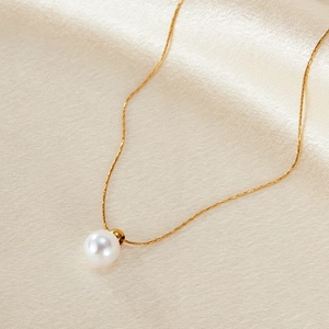 Elegant gold chain necklace featuring a white pearl pendant on premium silk background