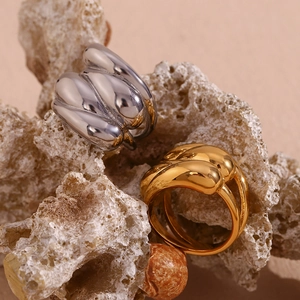 Close-up of gold and silver twisted dome rings on natural rock surface with soft lighting