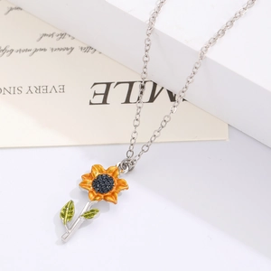 Gros plan du collier pendentif tournesol avec pétales en émail jaune et chaîne argentée